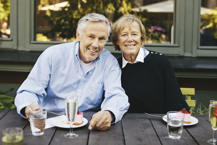 Portrait of happy senior couple having dessert at outdoor restaurant