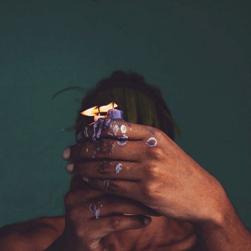 Close-up of woman covering face with burning candles