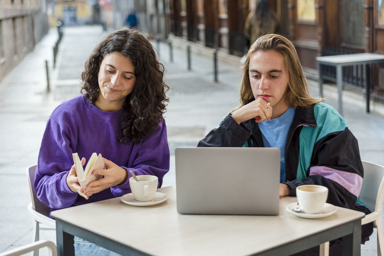 Young woman using digital tablet while sitting on table