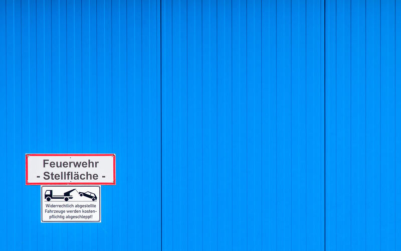 Close-up of information sign on blue corrugated wall