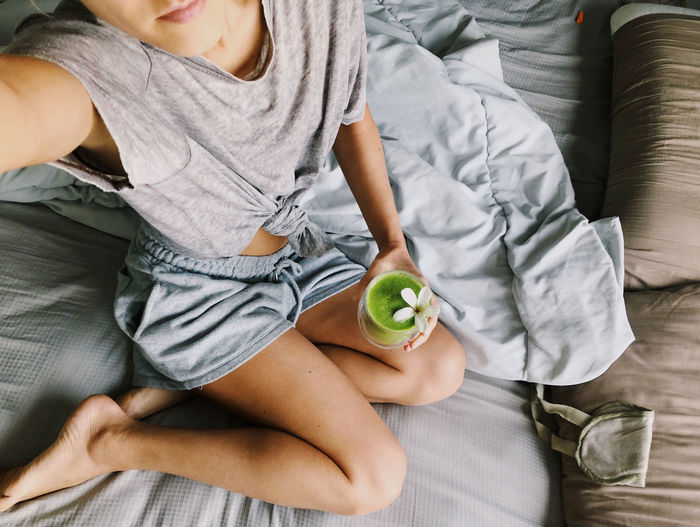Woman holding green smoothie in the morning