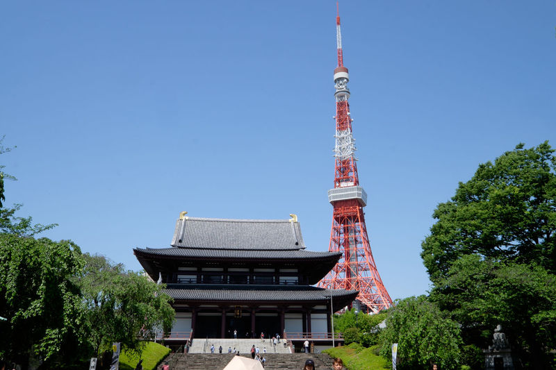 Tokyo tower by temple against clear sky in city