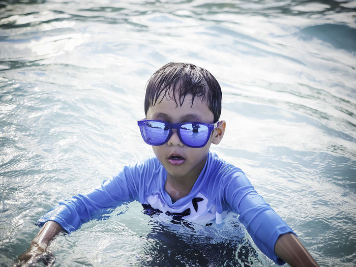 Portrait of boy wearing sunglasses swimming in pool