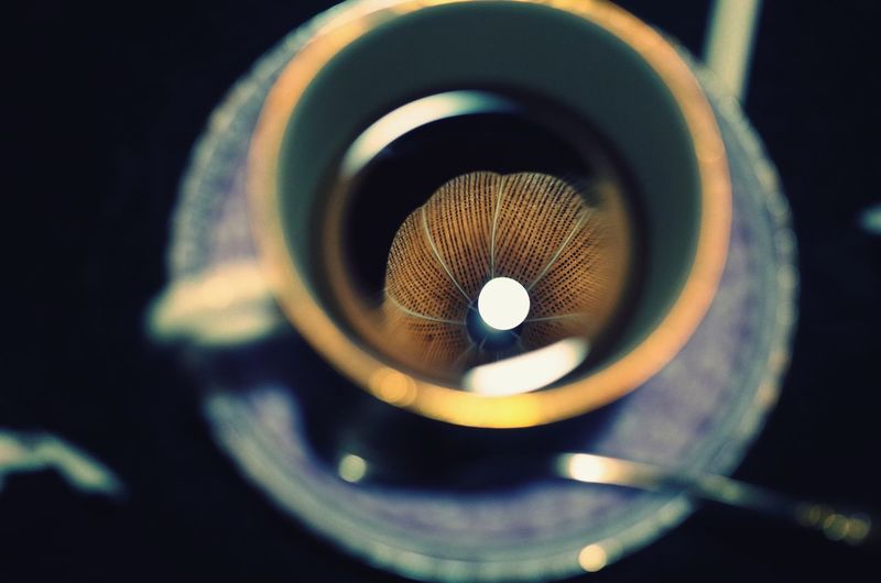 Overhead view of reflection of lamp shade in tea cup