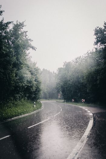 Road amidst trees against sky during rainy season