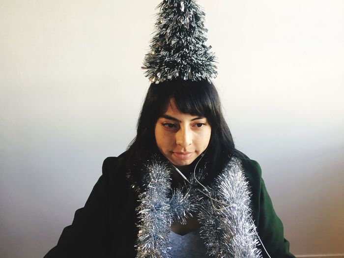 Woman with christmas decorations at home against wall
