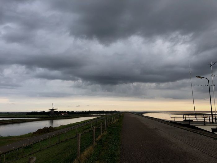 Road by street against cloudy sky