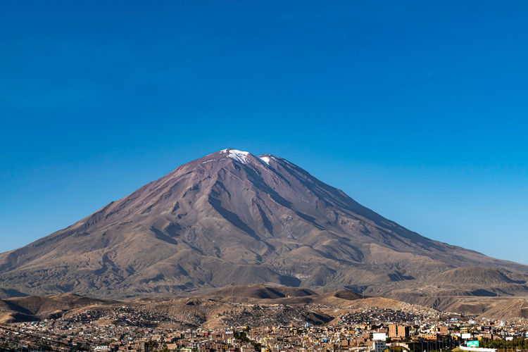 Scenic view of the volcano el misti looming over the city of arequipa, peru against blue sky 