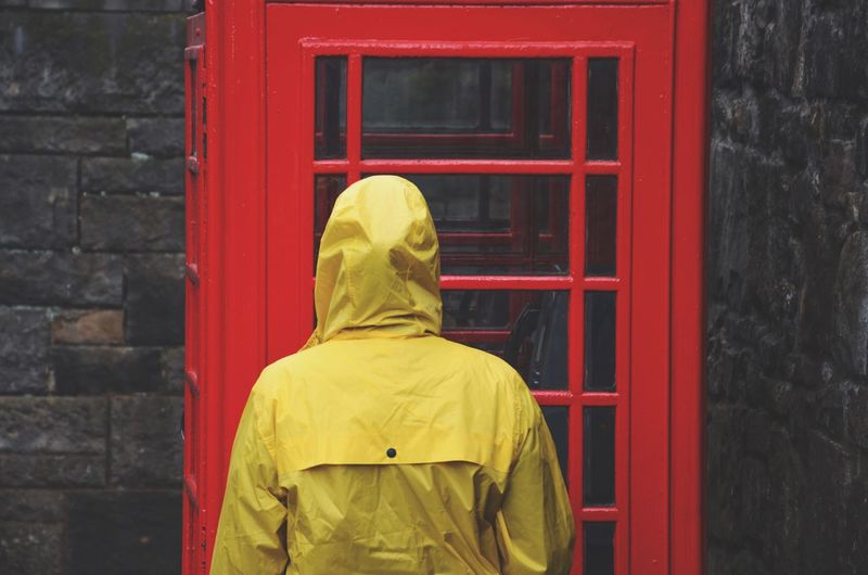 Rear view of person standing against red telephone booth