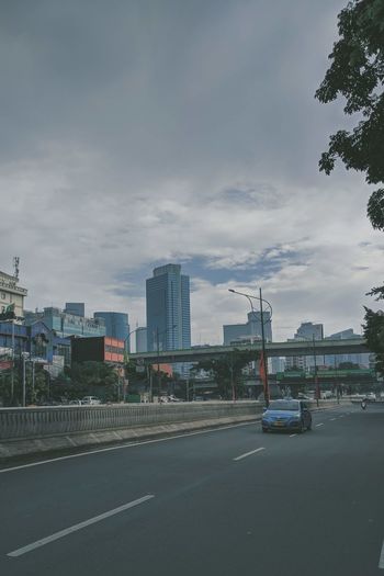Cars on road against sky in city