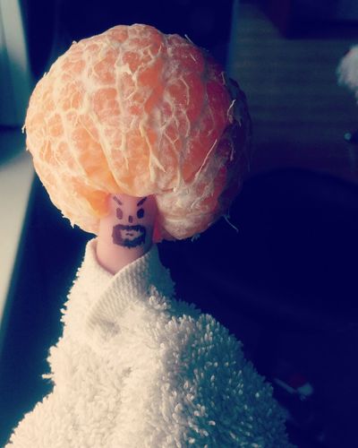 Close-up of orange on thumb with anthropomorphic face wrapped in napkin