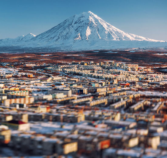 Tilt-shift image of cityscape against snow covered mountains