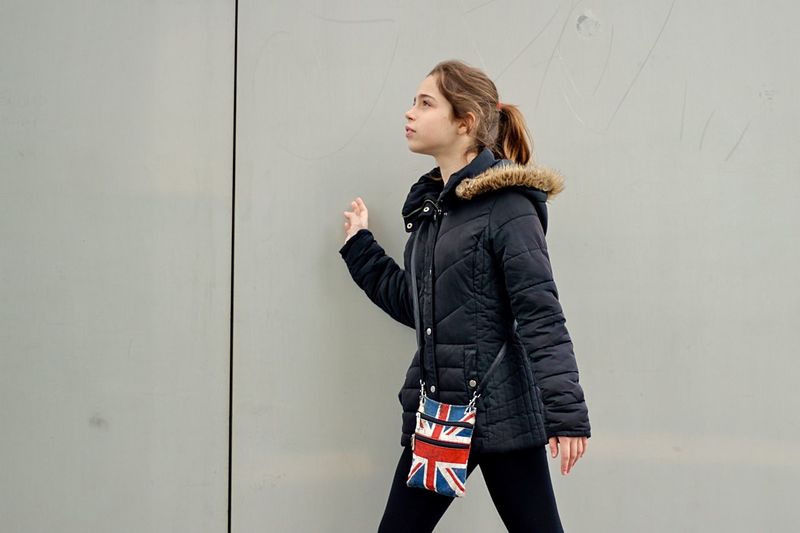 Teenage girl walking by gray wall