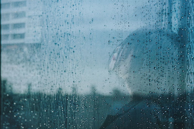 Side view of woman reflecting on wet mirror during rainy season