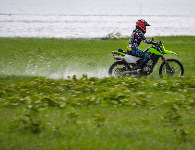 Woman riding her dirt-bike through wetlands near pak chong / thailand