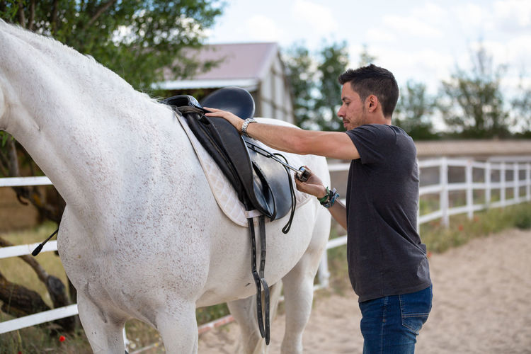 Midsection of man riding horse in ranch