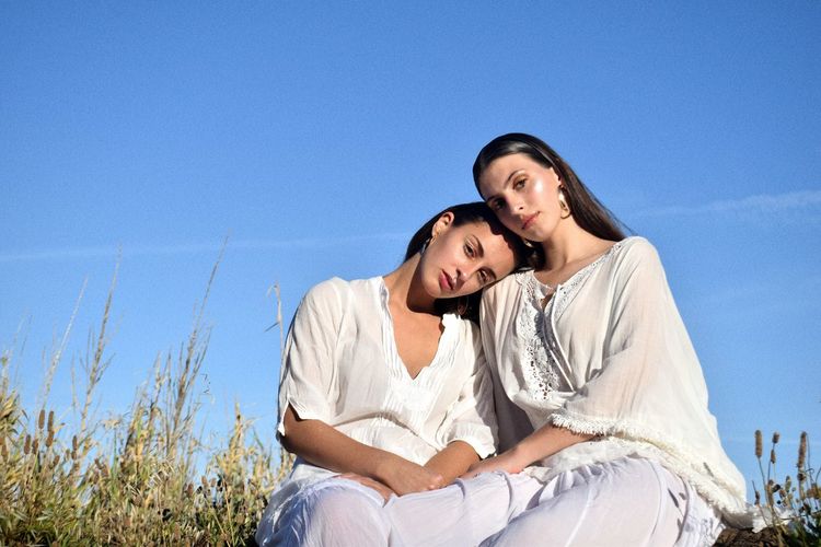 Portrait of lesbian couple against blue sky