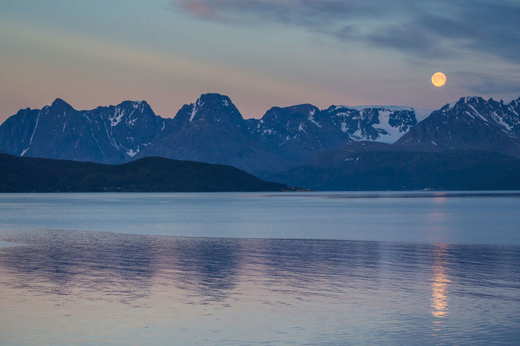 Scenic view of lake and mountain range against sky at dusk