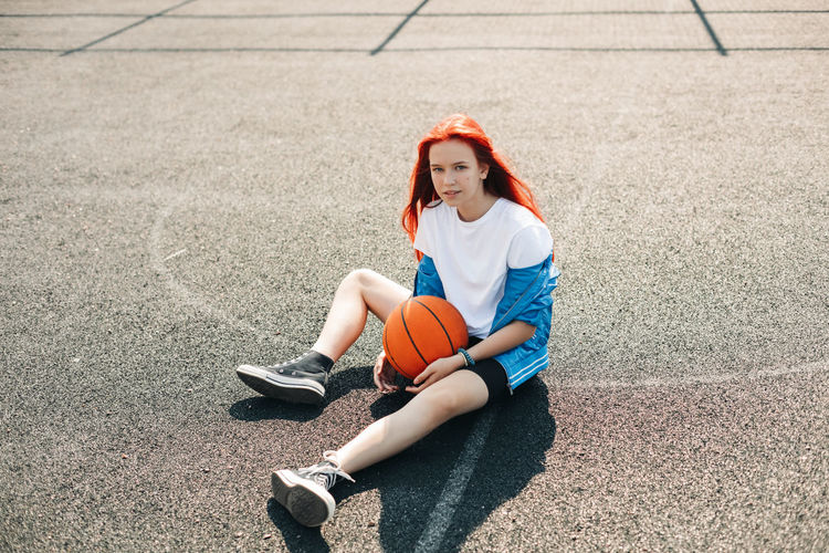 A charming teenage girl with a basketball is resting after a workout. a girl on the sports field. 