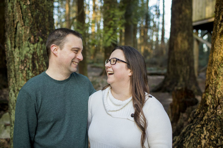 Cute couple laughing with one another in the forest.
