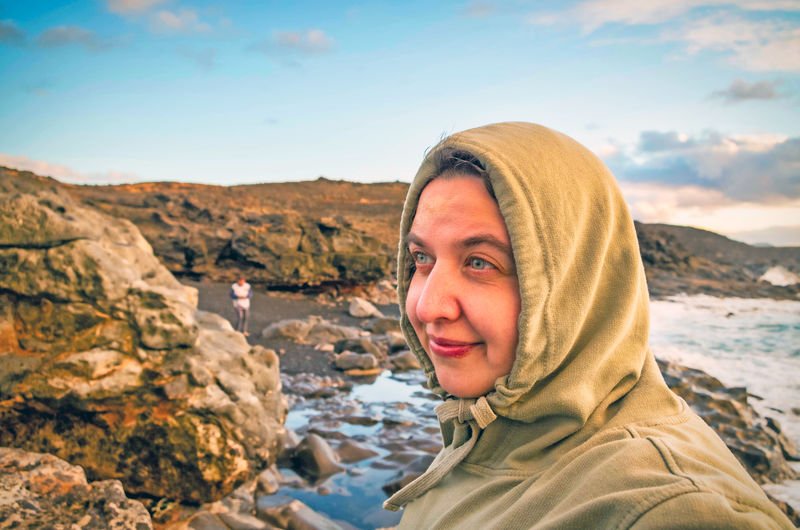 Smiling woman looking away while standing at beach