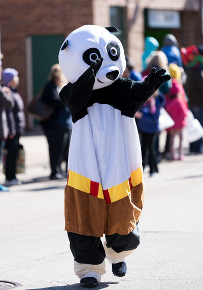 Person wearing panda costume while walking on footpath