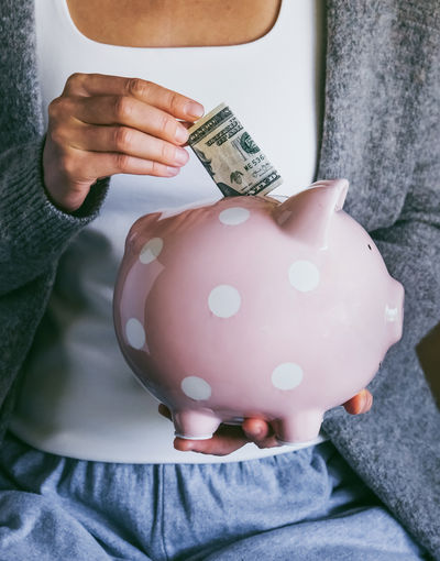 Woman putting bill in happy piggy bank. female saving money. economic crisis concept