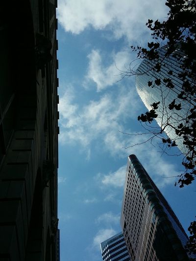Low angle view of skyscrapers against cloudy sky