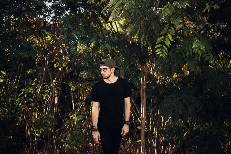 Young man standing amidst trees at forest