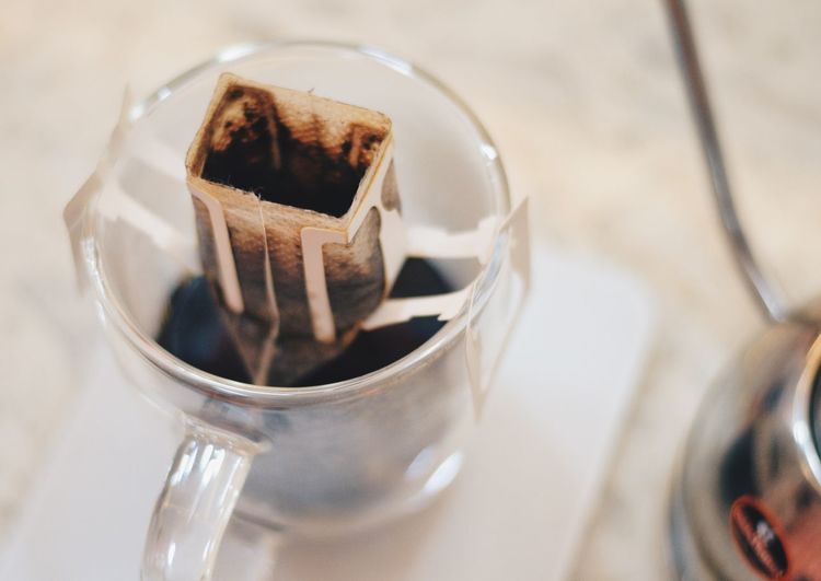 High angle view of filter over black coffee in glass on table