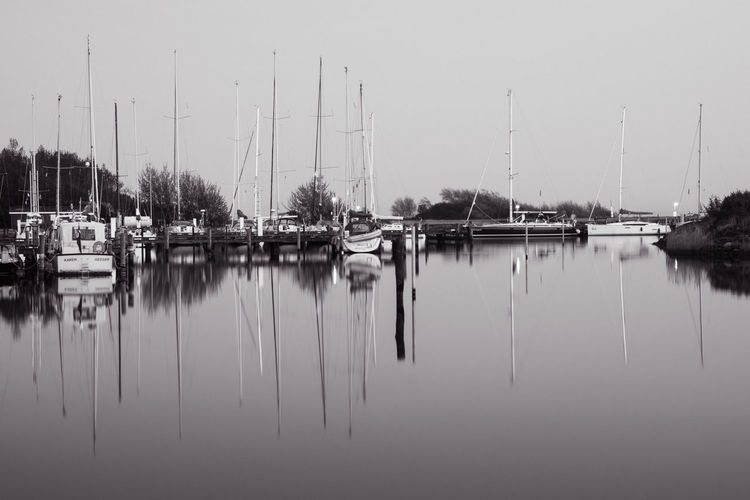 Sailboats moored in lake against sky
