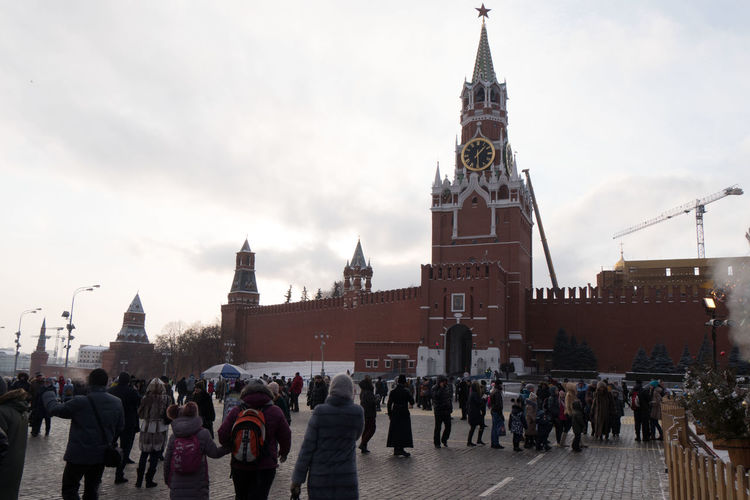 People at red square by spasskaya tower against sky