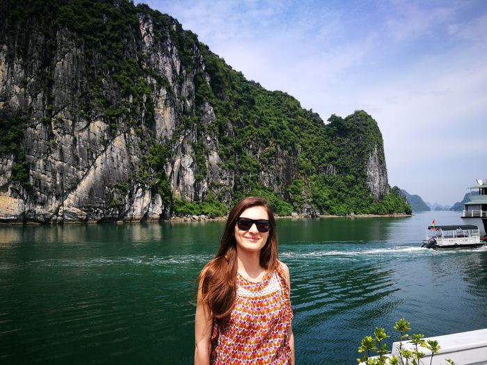 Portrait of young woman standing at halong bay against rock formation