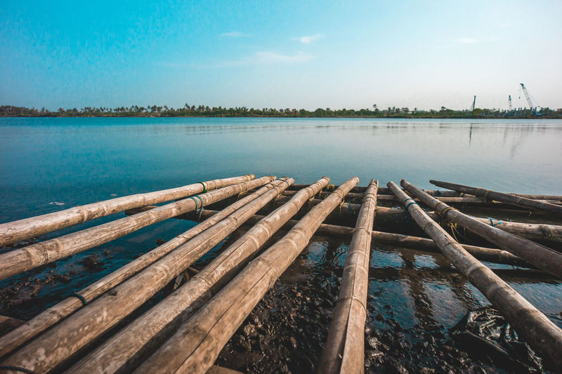 Wooden posts on lake against sky