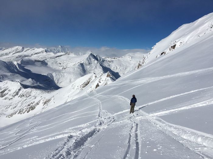 Teenage boy skiing on snowcapped mountain against sky