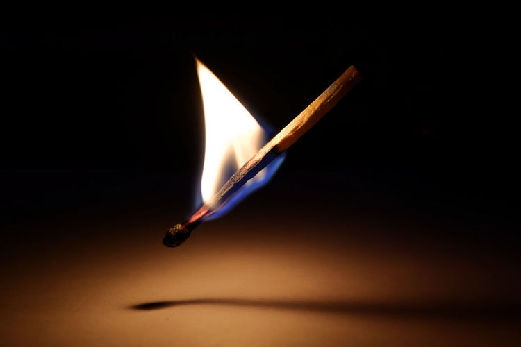 Close-up of burning matchstick against black background