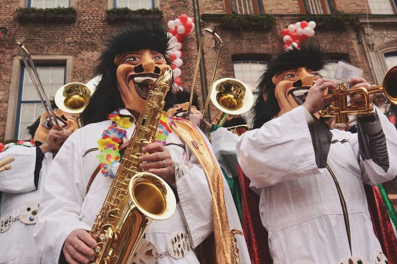 People wearing masks while playing saxophone and trumpet during carnival