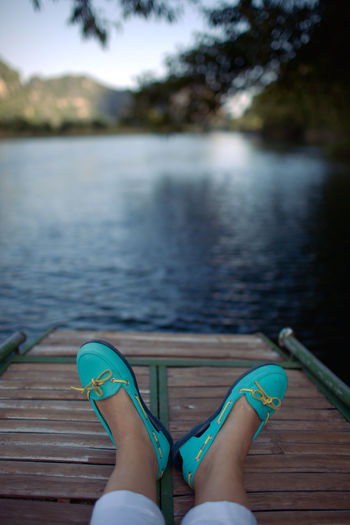 Low section of woman relaxing on pier over lake