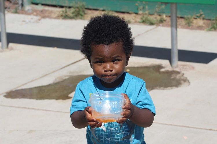 Portrait of cute boy drinking juice outdoors