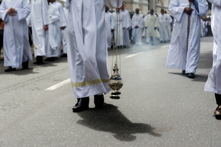 Priest is using a thurible to exhale incense during the corpus christ procession 