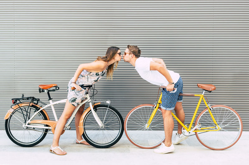 Side view of couple with bicycles kissing outdoors