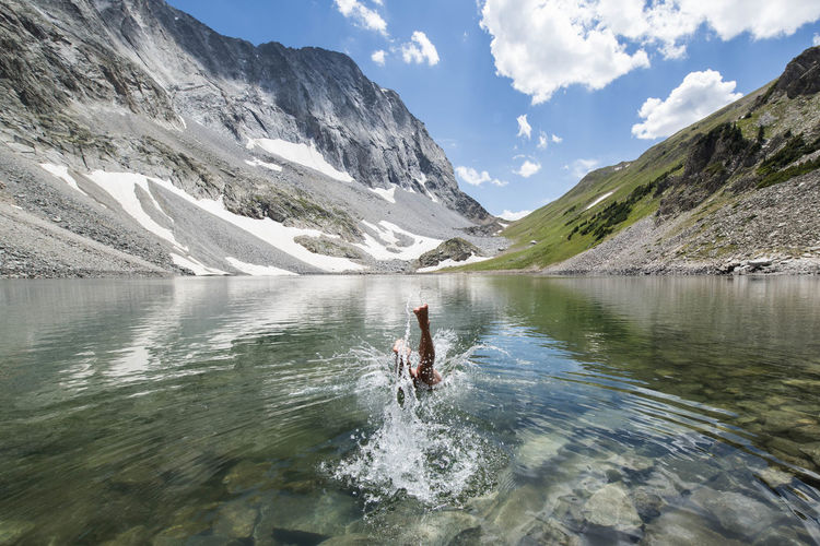 Woman diving in lake amidst mountain