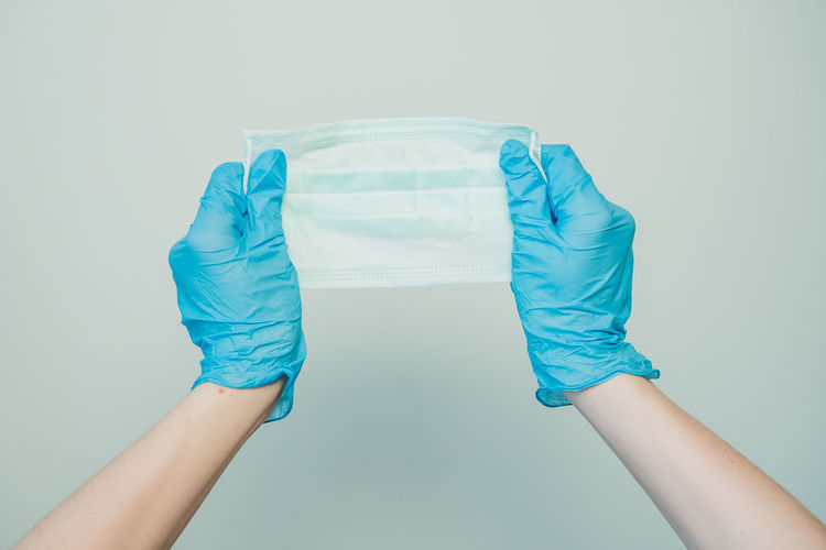 Low section of person holding blue glass against white background