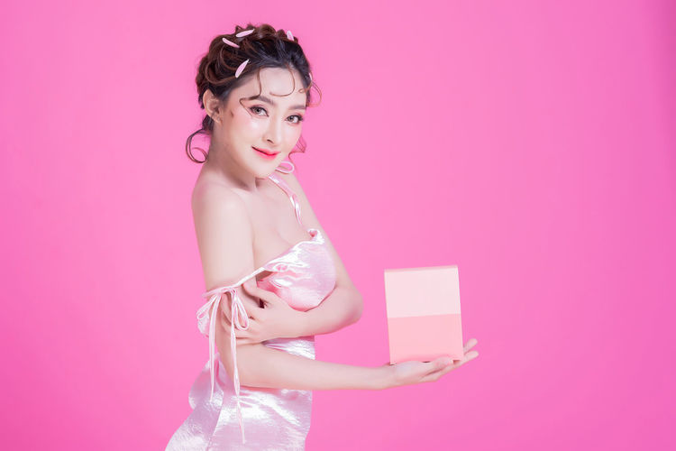 Portrait of a beautiful young woman against pink background