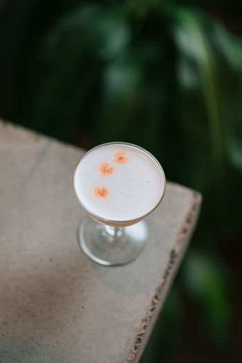 From above of glass pisco sour alcoholic cocktail made of liquor with freshly squeezed lime juice with syrup and egg white