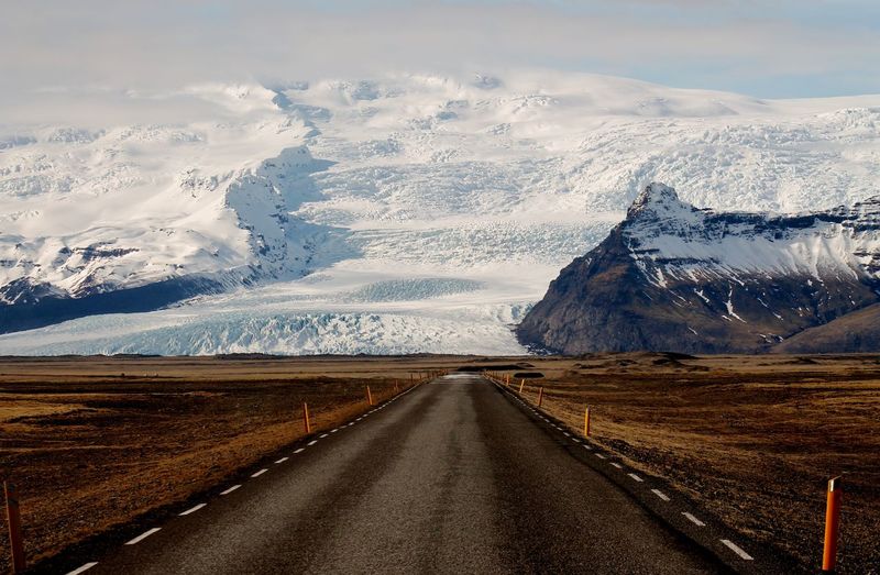 Empty road against snowcapped mountains