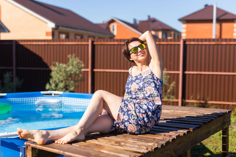 Smiling woman sitting on table by wading pool