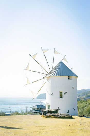 Traditional windmill on beach against clear sky
