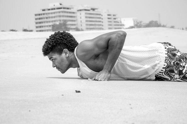 Side view of determined young man exercising at beach