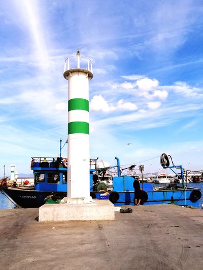 Lighthouse by harbor against sky